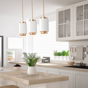 3 White and brushed gold Ingrid pendants hanging above a kitchen island.